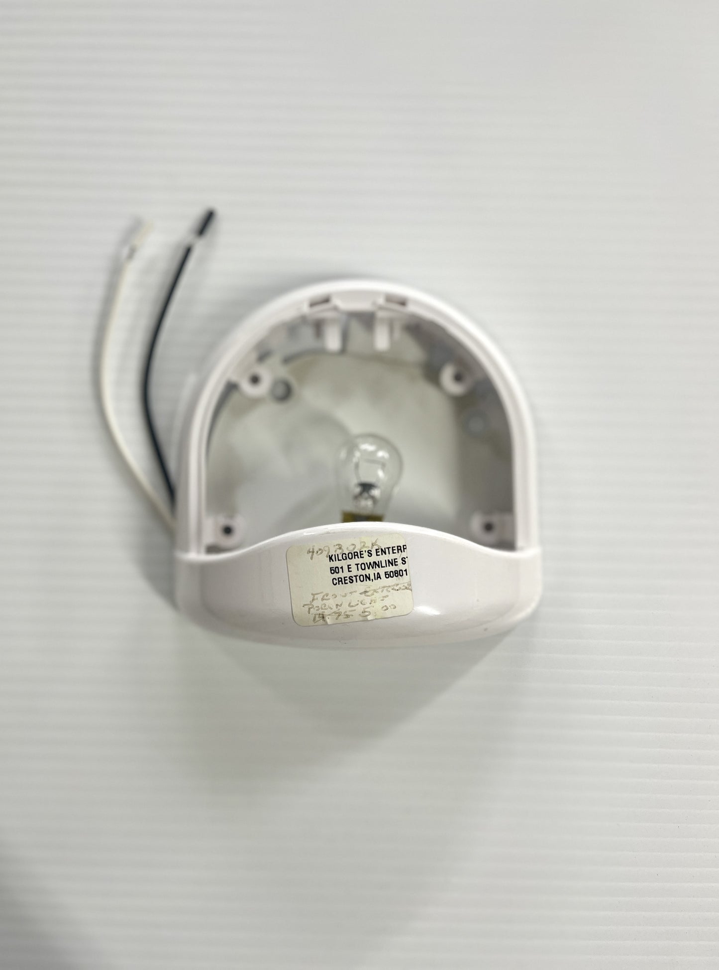 A white porch light fixture without a lens, mounted on a wall.