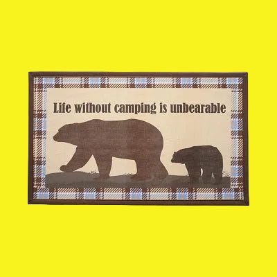 A rectangular accent rug with a plaid pattern and the text 'Life Without Camping Is Unbearable' printed on it, featuring images of bears in a forest setting.