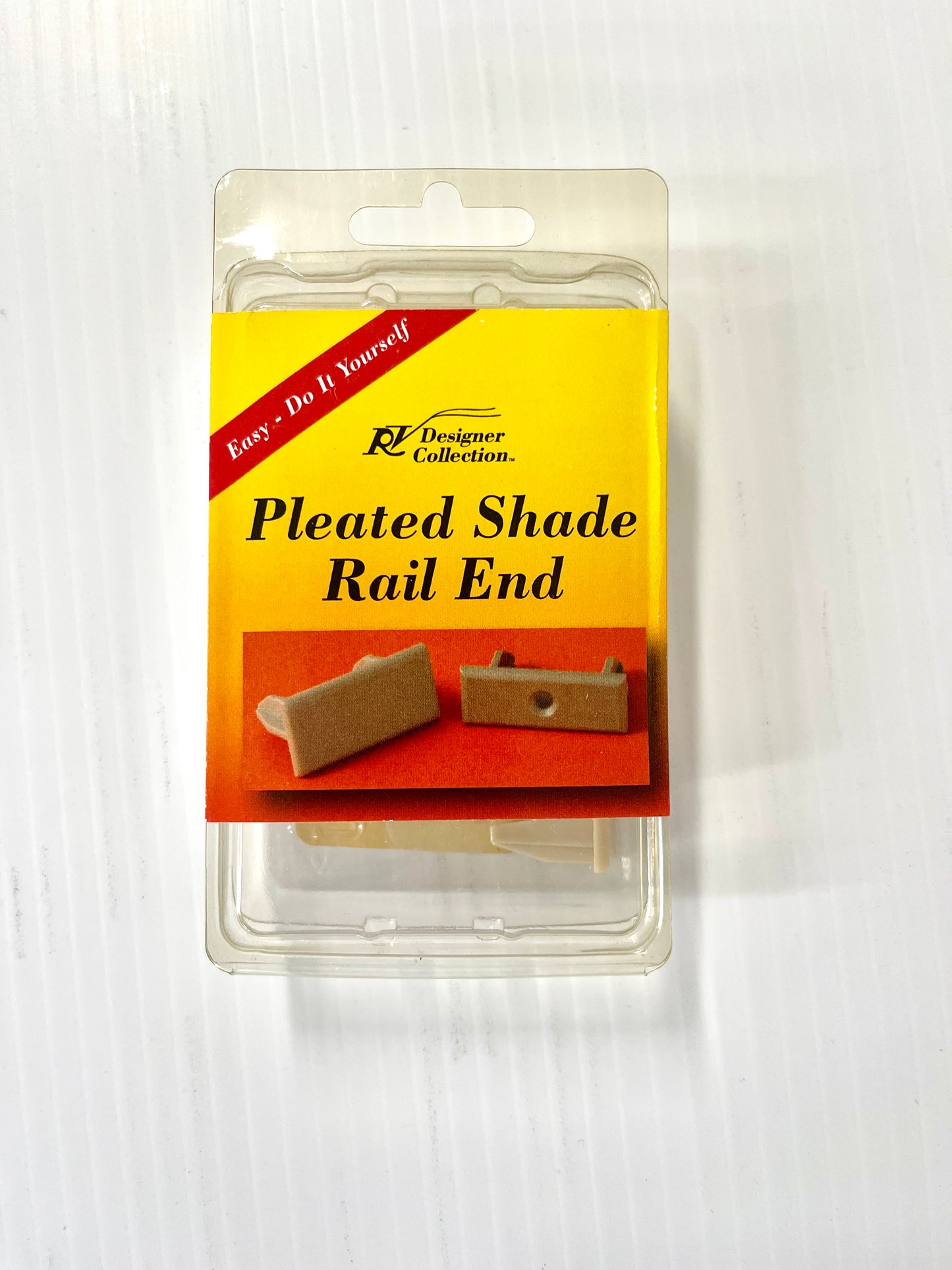Packaging for RV Designer Pleated Shade Rail End, showing the product through a clear plastic window, with a yellow and red label featuring the product name and a picture of the shade.