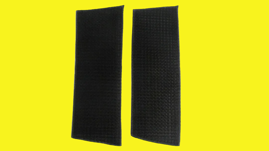 Two black air conditioner filters laid out on a yellow background.