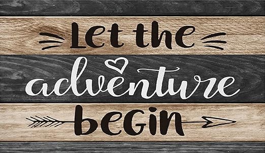 An absorbent mat with the text 'Let the adventure begin' printed in a cursive white font, surrounded by decorative elements like hearts and arrows, laid out on a wooden background.