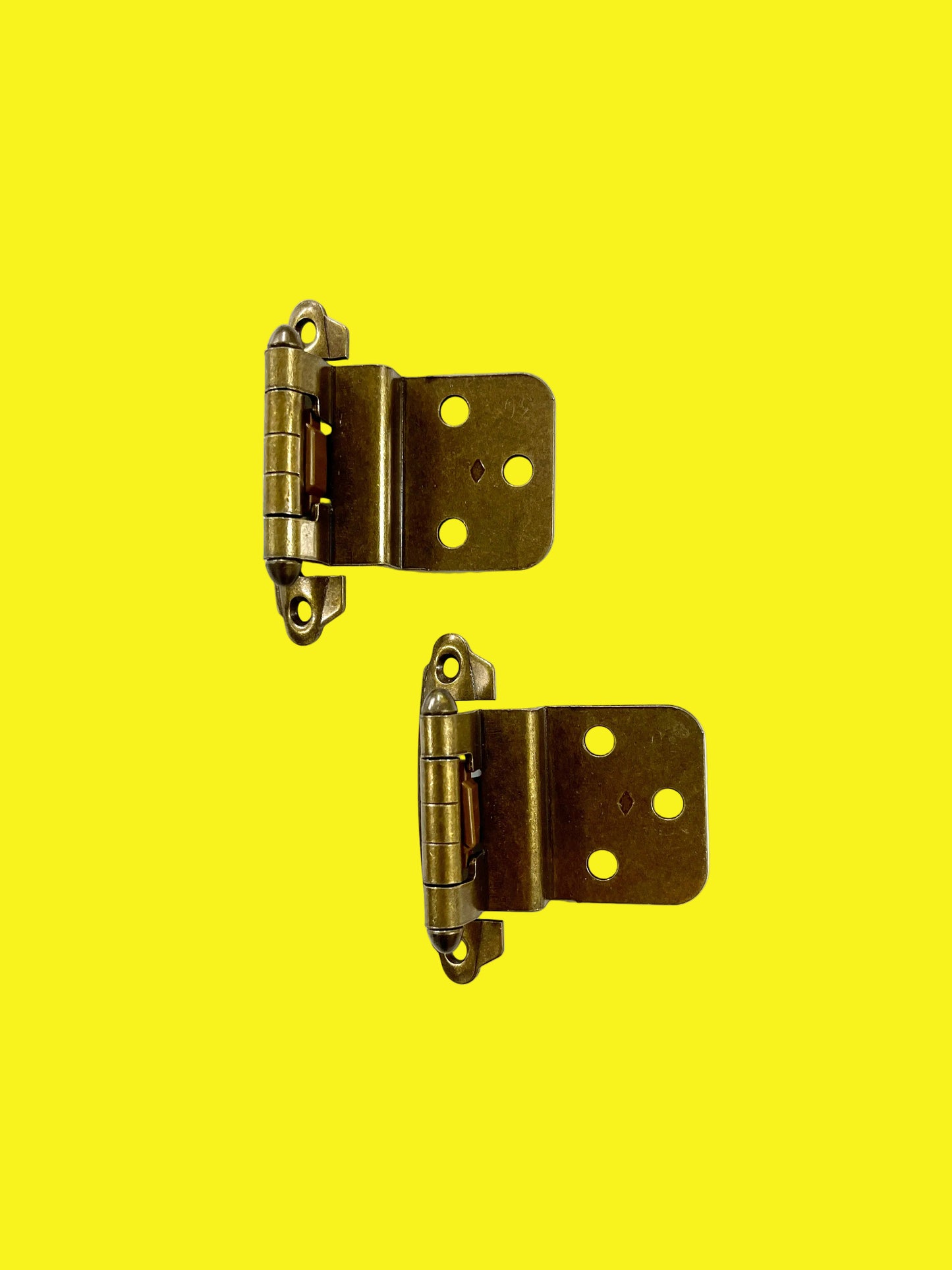A photo of a pair of bronze-colored hinges with a 3/8 inch offset, placed against a yellow background.