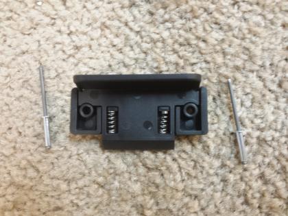 A black horizontal window latch with mounting hardware on a carpeted surface.