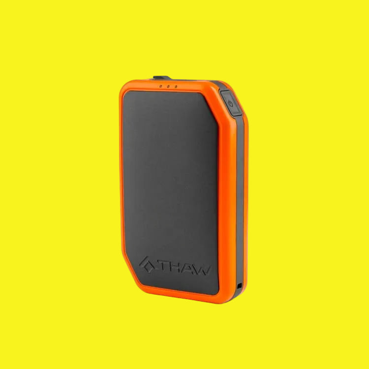 Gray and orange rechargeable hand warmer on a yellow background.