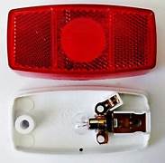 A red side marker light with a white backing, including a bulb and a plastic housing, separated into two parts.
