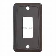 A brown switch plate cover with a single opening, featuring a rectangular shape with a visible brand logo on the lower right corner.