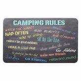 A rectangular, black kitchen mat with a list of 'Camping Rules' printed in various colors, such as blue, green, and teal, with a foam center and non-slip backing.