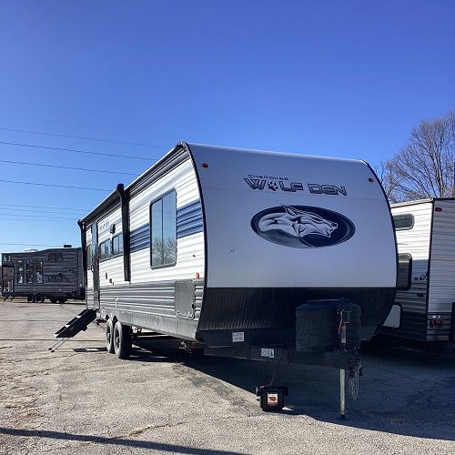 A blue and white bumper hitch camper with 'Wolf Den' on the front.