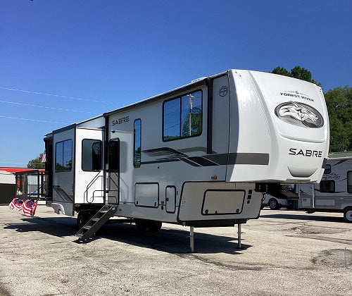 White and black RV with 'Sabre' branding on a clear day.