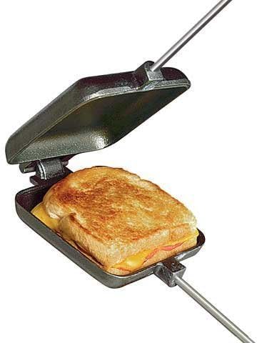 Cast iron pie iron showing a grilled cheese sandwich inside. Used for cooking over an open fire.