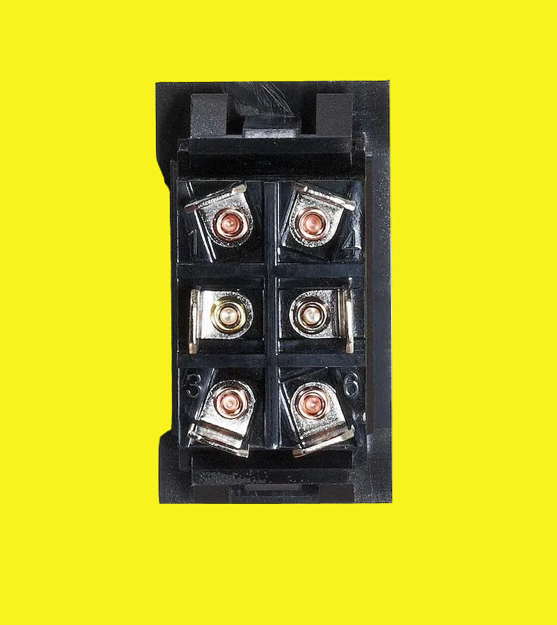 A black switch with six screw terminals, shown from a top-down view on a yellow background.