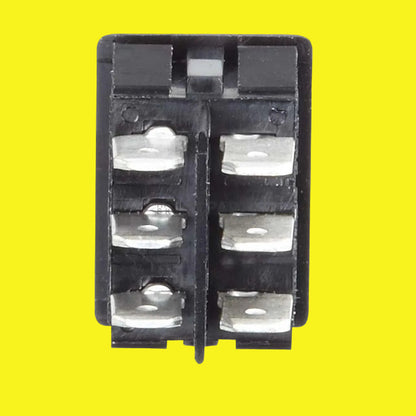 A black electrical switch with six terminals on a yellow background.