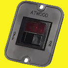 A close-up of a dark gray ATWOOD electrical switch with a red illuminated display window.