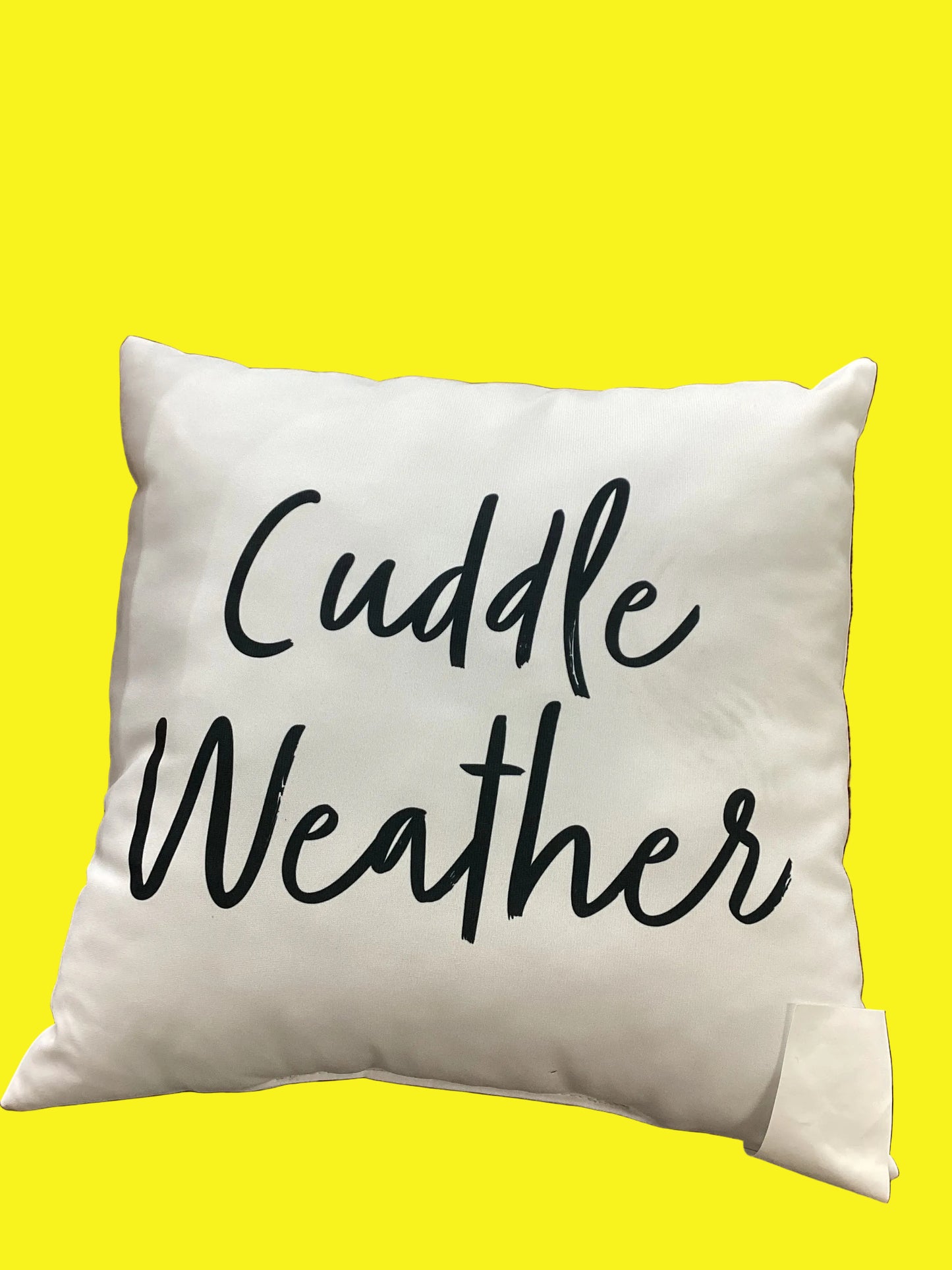 A white pillow with black letters that say "Cuddle Weather"