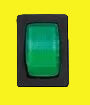 A square black rocker switch with a prominent green illuminated button, shown against a plain yellow background.